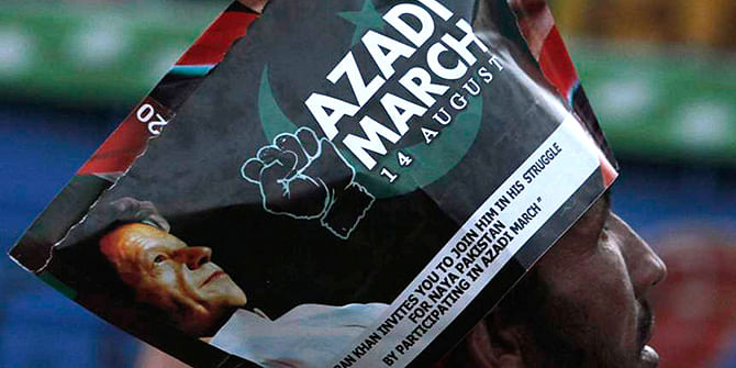 A supporter of chairman of the Pakistan Tehreek-e-Insaf (PTI) political party Imran Khan wears a poster on his head as he listens to his speech a Freedom March in Islamabad. Photo: Reuters