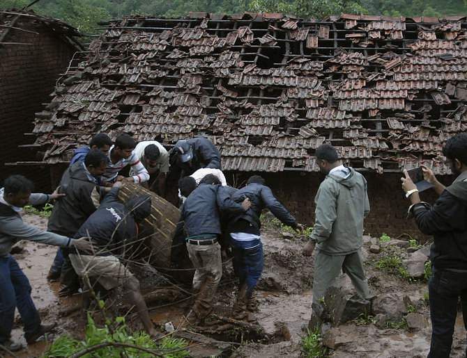 Rescue workers and volunteers clear the debris from the site of a landslide at Malin village in the western Indian state of Maharashtra July 30, 2014. Heavy rain triggered a landslide in India on Wednesday burying up to 150 people and rescuers were struggling through mud to try to reach them, a disaster official said. Photo: Reuters