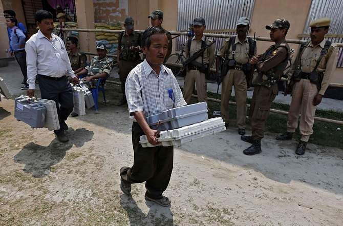 Election officials carry Electronic Voting Machines (EVM) as Indian security personnel stand guard at a distribution centre ahead of general elections in Jorhat district, in the northeastern Indian state of Assam April 6, 2014. Photo: Reuters 