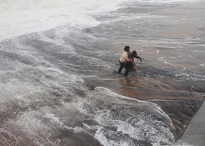 A man carries his wife to a safer ground after a wave hits a beach in Gopalpur in Ganjam district in the eastern Indian state of Orissa October 12, 2014. Photo: Reuters