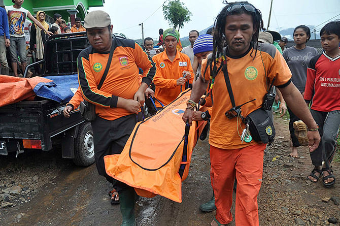 Rescue workers carry the body of a landslide victim at Pasuruhan village in Wonosobo December 12, 2014, in this photo taken by Antara Foto. Heavy rain caused a landslide early Friday in Pasuruhan village, with a citizen killed when a 50-meter high cliff hit the road. Picture taken December 12, 2014. Photo: Reuters