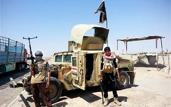 Al-Qaeda inspired militants stand with captured Iraqi Army Humvee at a checkpoint outside Beiji refinery, some 250 kilometers north of Baghdad, Iraq, on June 19, 2014. Photo: AP