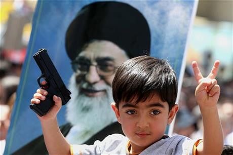 An Iraqi boy living in Iran holds a toy gun and flashes a victory sign in front of a poster of the Iranian Supreme leader Ayatollah Ali Khamenei in a demonstration against Sunni militants and to support the Grand Ayatollah Ali al-Sistani, Iraq's top Shia cleric, in Tehran on June 20. Photo: AP