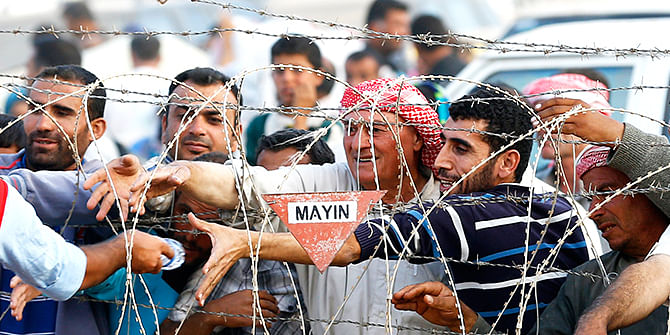 Syrian Kurdish men try to get water which is distributed by Turkish Red Crescent as they wait behind the border fences to cross into Turkey near the southeastern town of Suruc in Sanliurfa province September 27, 2014. Photo: Reuters