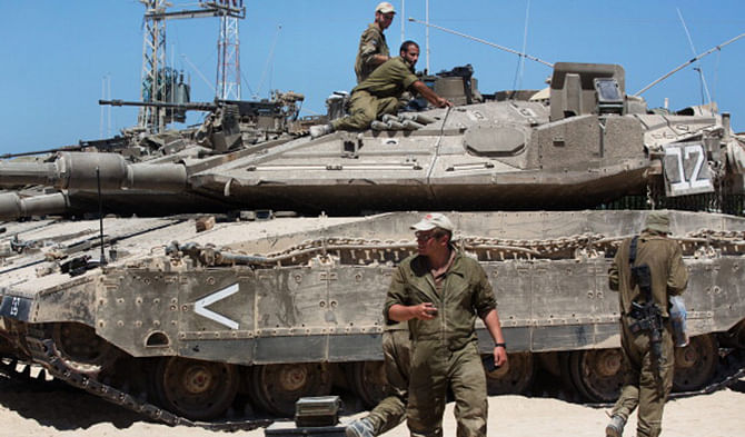 Israeli soldiers work on their Merkava tanks in an army deployment area near Israel's border with the Gaza Strip on July 11. Photo: Getty Images 