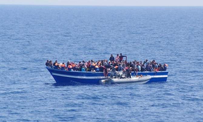 A boat filled with migrants receives aid from an Italian navy motor boat off the coast of Sicily in June. Photo: AP