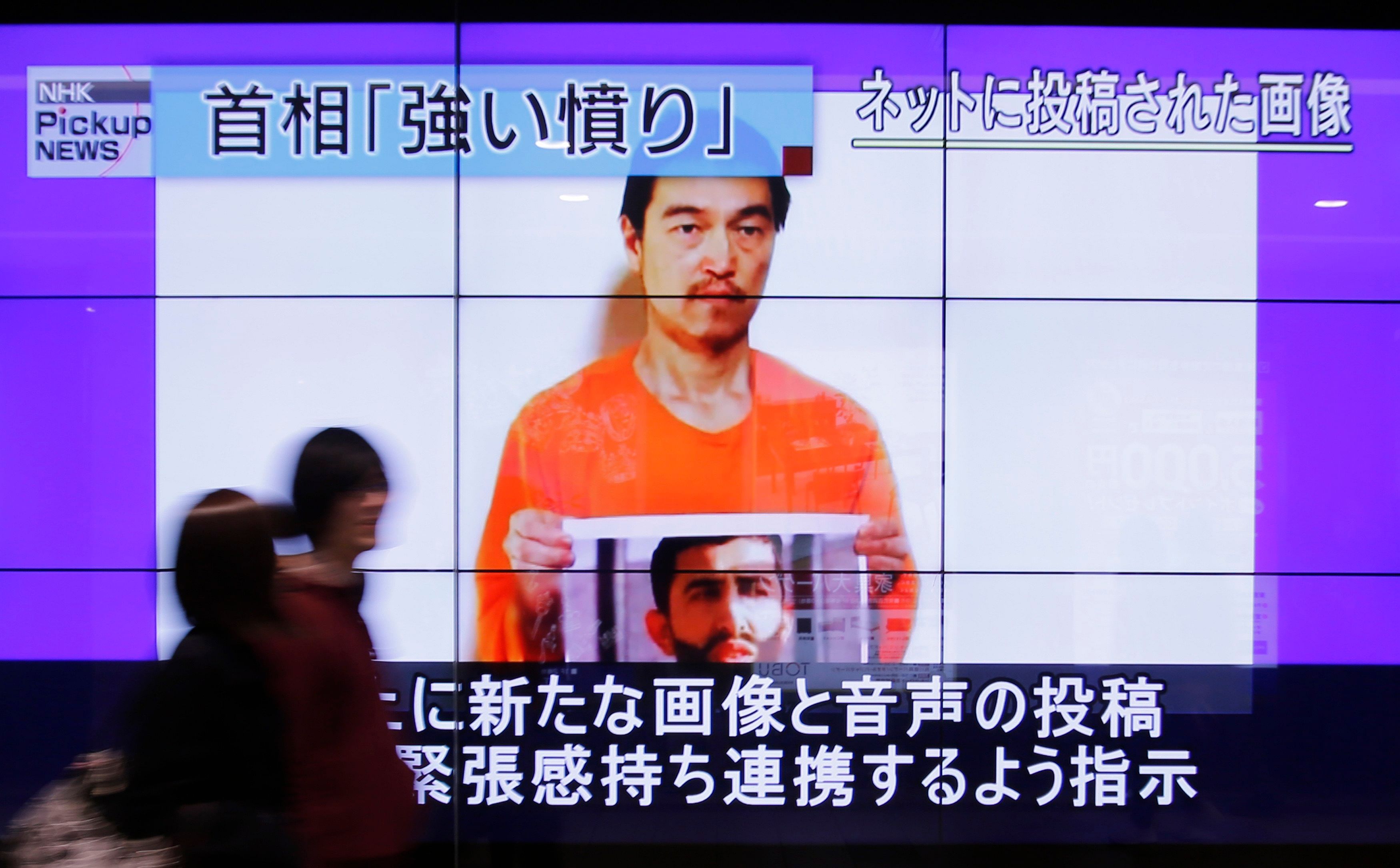 People walk past television screens displaying a news program, about an Islamic State video showing Japanese captive Kenji Goto, on a street in Tokyo January 28, 2015. Photo: Reuters