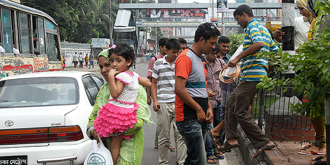 Pedestrians in the capital in many cases tend not to bother for the traffic signals, instructions of the police and even the rules. This Star file photo shows people are crossing the Kazi Nazrul Islam Avenue at Karwan Bazar where it is not allowed.  