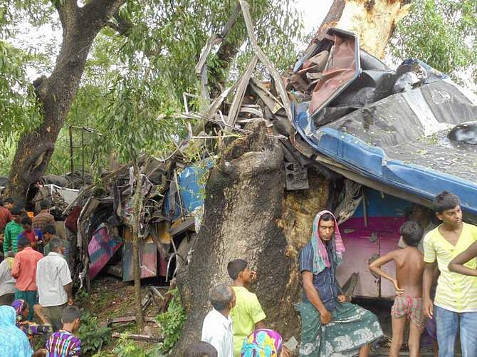People gather beside a damaged bus of Sohag Paribahan that hit a roadside tree in Jhikorgachha upazila of Jessore Tuesday morning. 10 passengers of it were killed in the road accident. Photo: STAR