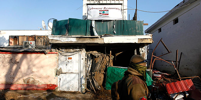 An Afghan security personnel walks past a Lebanese restaurant, the site of a suicide bombing, in Kabul January 18, 2014. Up to 15 people, mostly foreigners, were killed on Friday when a suicide bomber blew himself up outside the popular Lebanese restaurant in the Afghanistan capital of Kabul, police said.