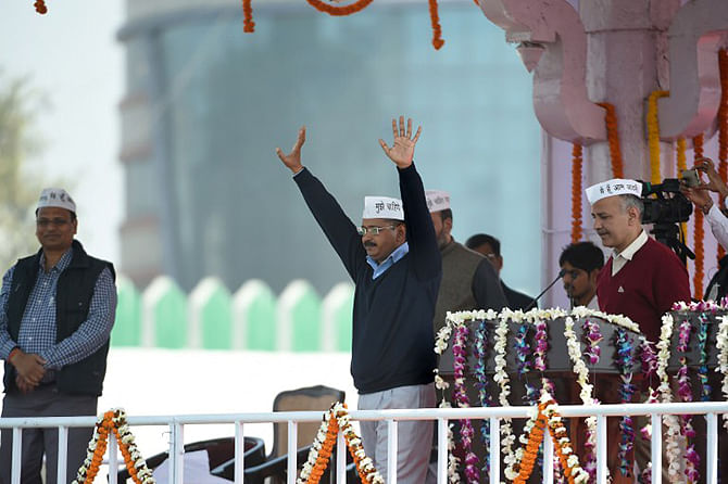 Aam Aadmi Party (AAP) president Arvind Kejriwal (C) greets his supporters as fellow Minister Manish Sisodia (R) looks on during his swearing-in ceremony as Delhi chief minister in New Delhi on February 14, 2015. Photo: AFP