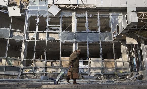 A woman pulls her shopping trolley as she walks past a building that was damaged by shelling in Donetsk, eastern Ukraine in this October 15, 2014 file photo. Photo: Reuters