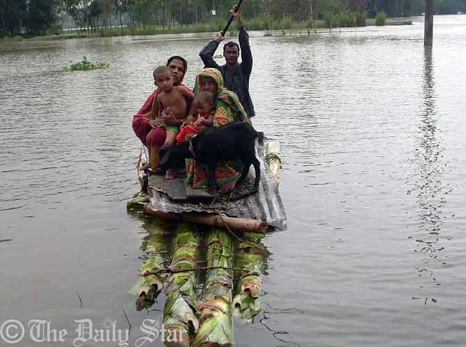 Flood-hit people leave houses as their village goes under overflow water of the Teesta river Thursday morning. Photo: STAR