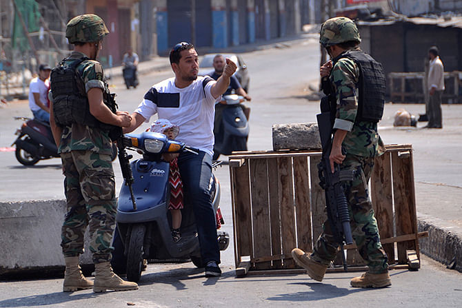 A civilian on a scooter talks to Lebanese army soldiers as he tries to make his way through a blocked road in Lebanon's northern port city of Tripoli August 5, 2014. Photo: Reuters
