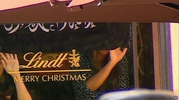Apparent hostages inside the cafe were seen holding up a black flag with the Islamic creed on it. Photo taken from BBC