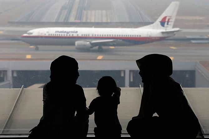 This Reuters file photo shows women and a girl look at a Malaysia Airlines plane on the tarmac of Kuala Lumpur International Airport in this March 13, 2014. 