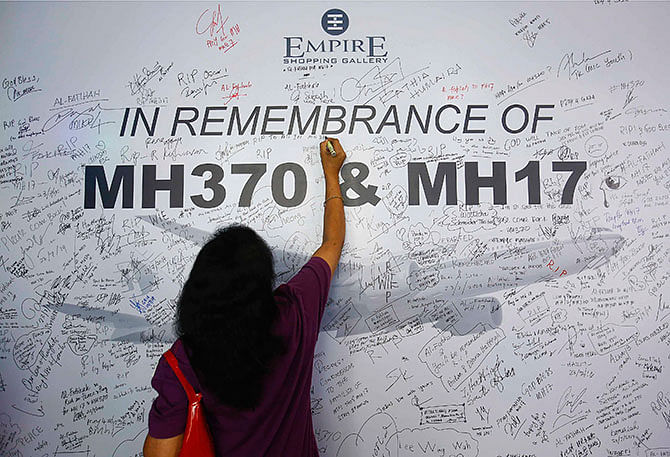 A woman writes a message on a dedication board for the victims of the downed Malaysia Airlines Flight MH17 airliner and the missing Flight MH370, in Subang Jaya outside Kuala Lumpur July 23, 2014. Photo: Reuters