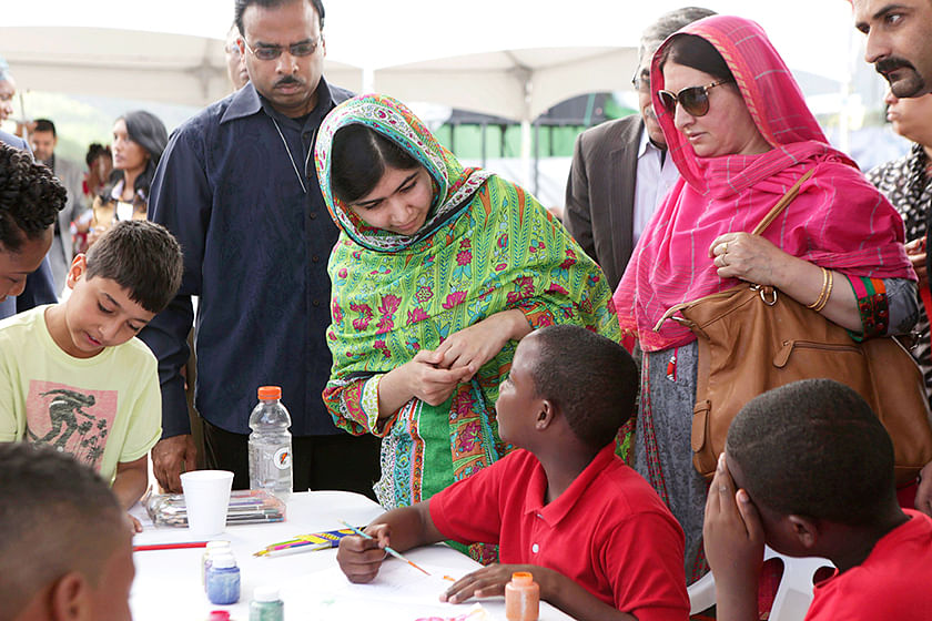 Pakistani schoolgirl activist Malala Yousafzai (C) talks to a boy taking part in a workshop at the Emancipation Village at Queen's Park Savannah, in Port of Spain July 31, 2014. Seen at left is Malala's brother Atal Khan Yousafzai and at right is her mother Toorpekai Yousafzai. Photo: Reuters