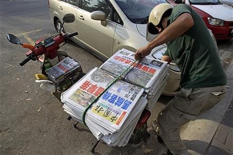 A newspaper delivery man prepares to unload Chinese newspapers carrying headline stories and pictures of Thursday's Malaysia Airlines plane shot down, in Shah Alam, outside Kuala Lumpur, Malaysia, Friday. Photo: AP