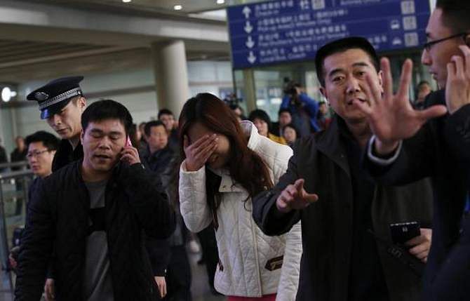 A woman (C), believed to be the relative of a passenger onboard Malaysia Airlines flight MH370, covers her face as she cries at the Beijing Capital International Airport in Beijing on March 8, 2014. Photo: Reuters