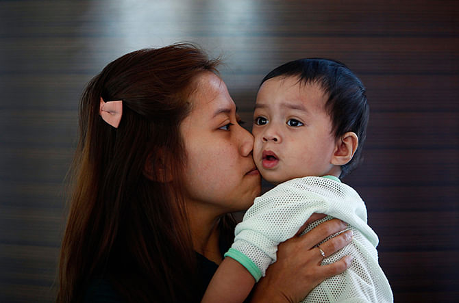 Erny Khairul, whose husband Mohd Khairul Amri Selamat was onboard the missing Malaysia Airlines flight MH370, kisses her daughter inside a hotel they are staying at in Putrajaya March 11, 2014. Photo: Reuters