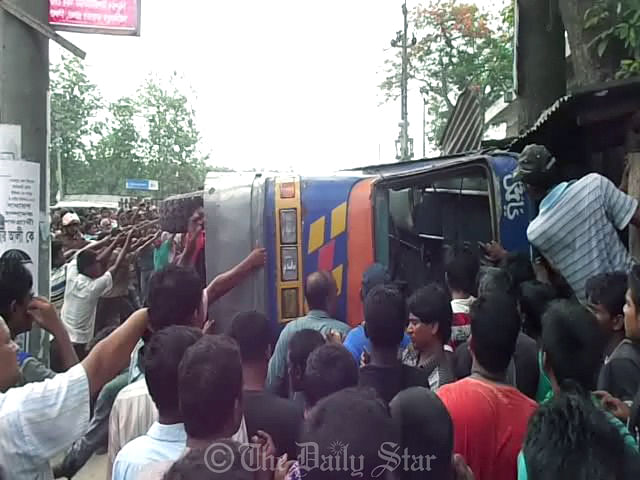 Locals try to move the bus that overturned while taking a U-turn in full speed at Meherpur College Intersection in Meherpur town on Thursday. Four people were killed and 30 injured in the accident. Photo: Star