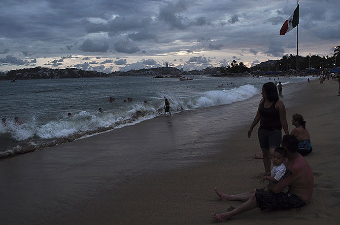 People spend time at the beach in Acapulco, as Hurricane Odile churns far off shore September 14, 2014. The Mexican government declared a hurricane warning for southern Baja and a tropical storm warning for parts of the Pacific coast. Photo: Reuters