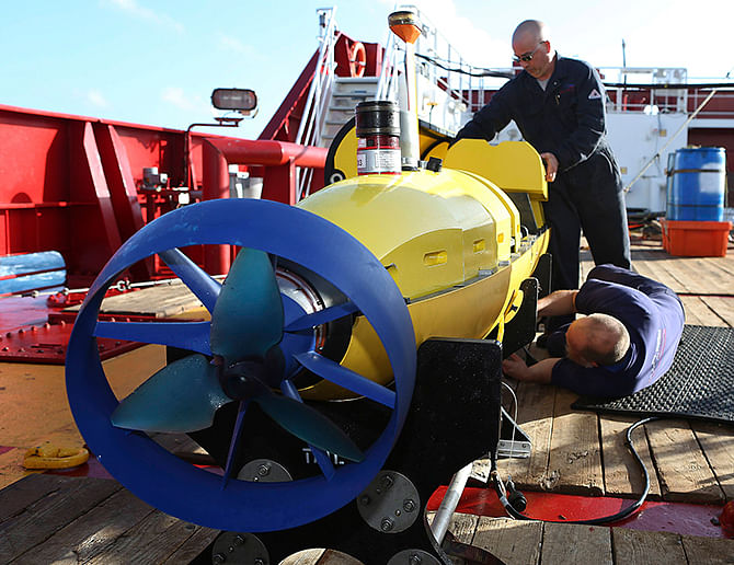 Evan Tanner and Chris Minor (standing) from Phoenix International conduct pre-deployment checks of the Phoenix Autonomous Underwater Vehicle (AUV) Artemis off the deck of Australian Defence Vessel Ocean Shield into the water to search for the missing Malaysia Airlines Flight MH370 in the Southern Indian Ocean, in his image released by the Australian Defence Force on Sunday. Photo: Reuters