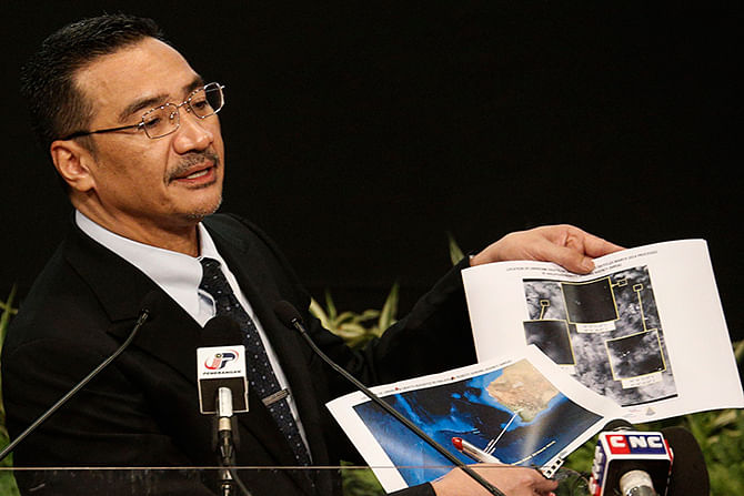 Malaysia's acting Transport Minister Hishammuddin Hussein holds satellite images as he speaks about the search for the missing Malaysia Airlines Flight MH370, during a news conference at Putra World Trade Center in Kuala Lumpur on Wednesday. Photo: Reuters