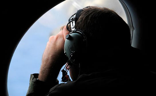A crew member aboard a Royal New Zealand Air Force (RNZAF) P-3K2 Orion aircraft looks out an observation window as they fly over the southern Indian Ocean to continue the search for missing Malaysian Airlines flight MH370. Photo: Reuters 