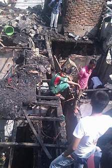People look at a burnt makeshift structure Wednesday afternoon. Photo: Shaheen Mollah