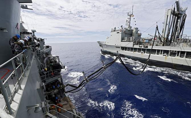 Crew aboard the Australian Navy ship HMAS Perth watch lines as they are refuelled by HMAS Success during a replenishment at sea, as they continue to search for missing Malaysian Airlines flight MH370 in this picture released by the Australian Defence Force April 10, 2014. 
