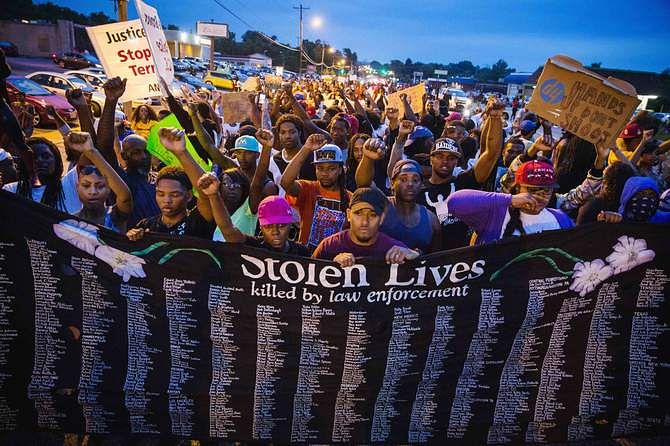 Protestors march and hold their fists aloft as they march during ongoing demonstrations in reaction to the shooting of Michael Brown in Ferguson, Missouri August 16, 2014. Photo: Reuters 