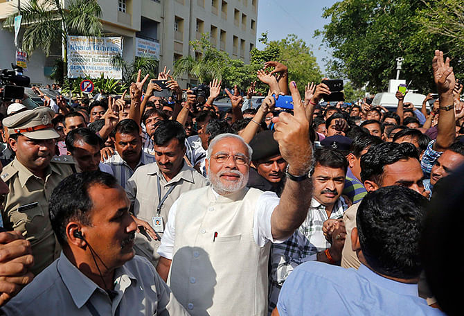 Hindu nationalist Narendra Modi (C), the prime ministerial candidate for India's main opposition Bharatiya Janata Party (BJP), shows his ink-marked finger to his supporters after casting his vote at a polling station during the seventh phase of India's general election in the western Indian city of Ahmedabad on Wednesday. Photo: Reuters