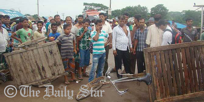Relatives of missing launch capsize victims block a road in front of Padma Rest House near the Mawa ghat in Lauhajang upazila of Munshiganj for an hour Tuesday morning. At least 120 people went missing as the launch sank in the Padma river Monday. Photo: STAR