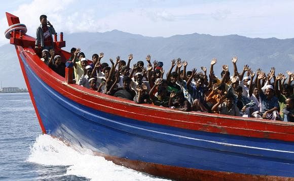 This Reuters photo taken on April 8, 2013 shows ethnic Rohingya refugees from Myanmar wave as they are transported by a wooden boat to a temporary shelter in Krueng Raya in Aceh Besar. 