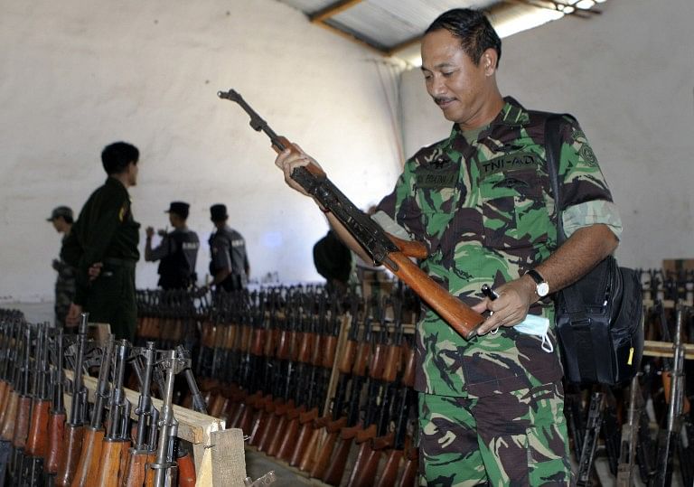 An unidentified diplomat tries a gun allegedly seized from ethnic Kokang rebels on display at a press conference held by Myanmar Police Force. Photo: AFP