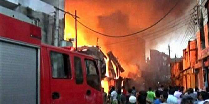 Onlookers gather in front of Shuhrawardi Market in Narayanganj city when a fire breaks out there early Wednesday. A fire brigade vehicle is seen standing beside the market. Photo: TV grab
