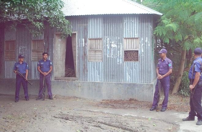 This Star photo taken on June 23 shows policemen guarding the house of Md Johurul Haque, a prosecution witness in the case against Jamaat-e-Islami chief Motiur Rahman Nizami for crimes against humanity, at Haria village in Santhia upazila of Pabna