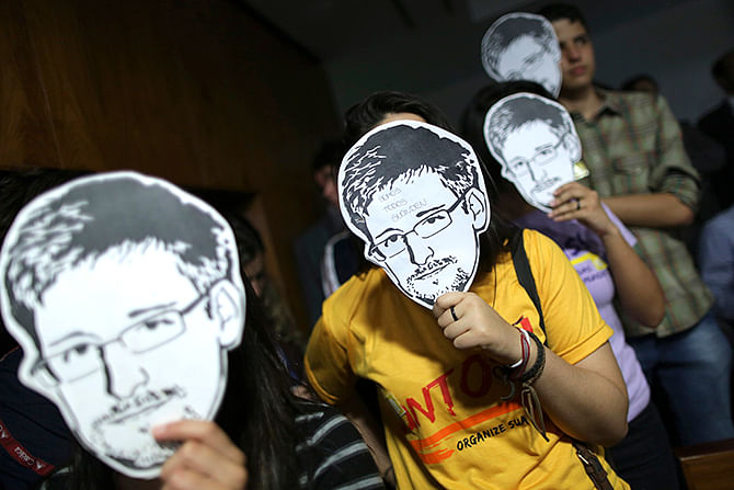 This Reuters photo taken on August 6, 2013 shows people wearing masks with pictures of former NSA contractor Edward Snowden during the testimonial of Glenn Greenwald, the American journalist who first published the documents leaked by Snowden, before a Brazilian Congressional committee on NSA's surveillance programs, in Brasilia.
