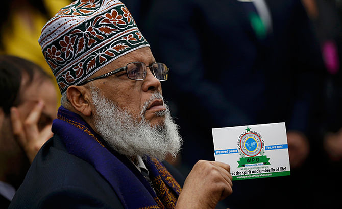 Imam Sheikh Sa'ad Musse Roble of Minneapolis, Minnesota holds up a card from the WPO World Peace Organization as he listens to US President Barack Obama during his speech before the White House Summit on Countering Violent Extremism in Washington, February 18, 2015. Photo: Reuters