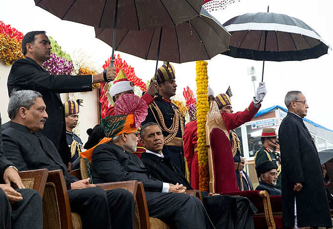 India's Prime Minister Narendra Modi (centre L) and U.S. President Barack Obama (centre R) sit under umbrellas watching India's Republic Day parade in the rain together from their review stand in New Delhi January 26, 2015. Photo: Reuters