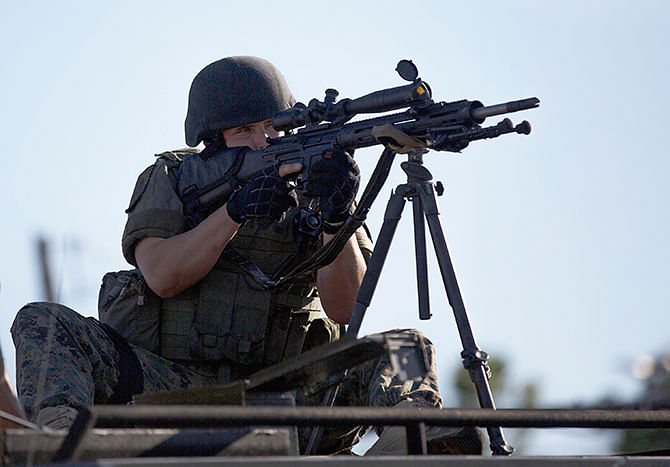 A riot police officer aims his weapon while demonstrators protest the shooting death of teenager Michael Brown, in Ferguson, Missouri in this file photo taken August 13, 2014.  U.S. President Barack Obama has ordered a review of the distribution of military hardware to state and local police out of concern at how such equipment has been used during racial unrest in Ferguson, Missouri. Photo: Reuters