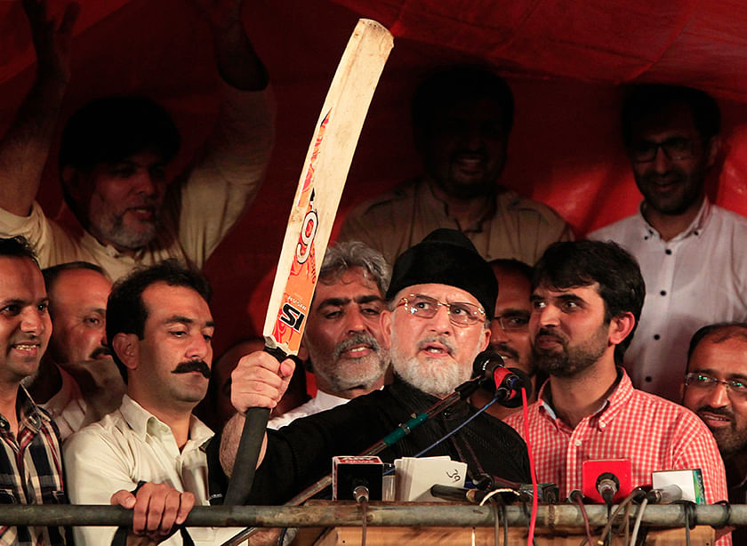Tahir ul-Qadri, Sufi cleric and opposition leader of political party Pakistan Awami Tehreek (PAT), raises a cricket bat while addressing supporters in front of Parliament House during the Revolution March in Islamabad September 5, 2014. Photo: Reuters
