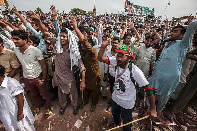 Supporters of Imran Khan, the Chairman of the Pakistan Tehreek-e-Insaf (PTI) political party, react as they listen to their leader in front of the Parliament house building during the Revolution March in Islamabad August 28, 2014. Photo: Reuters