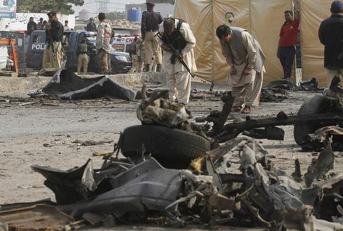 Security officials collect evidence at the site of an explosion in Karachi Thursday. An explosion targeting a bus full of Pakistani policemen killed 11 and injured 33 near the southern port city of Karachi. 