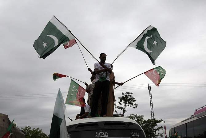 Supporters of Pakistan Tehreek-e-Insaf, a political party led by cricketer-turned-opposition politician Imran Khan, wave flags from the roof of a van as they arrive with the Freedom March in Islamabad August 16, 2014. Photo: Reuters