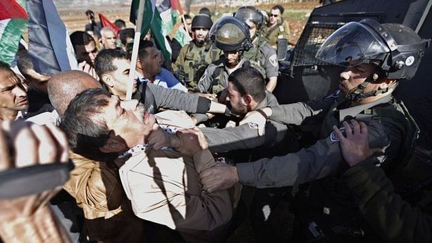 Photographs appeared to show Ziad Abu Ein (left) being held by the throat by an Israeli soldier. Photo: BBC