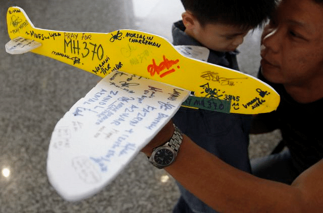 A man holds a model plane with well-wishing messages for the passengers of the missing Malaysian Airline plane at Kuala Lumpur International Airport, Malaysia, 15 March 2014. Photo: The Star