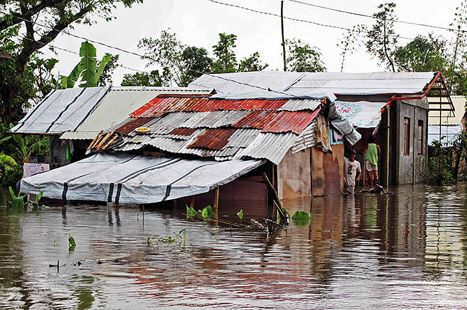 A resident looks out from his home sitting in floodwaters brought on by heavy rains from tropical storm Jangmi, locally called Seniang, in Palo town, Samar province December 30, 2014. Photo: Reuters